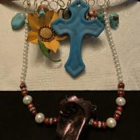 Leather belt choker with metal sunflower and a turquoise cross. Other decorative beads and turquoise added. The center has a tiny Jesus sculpture.